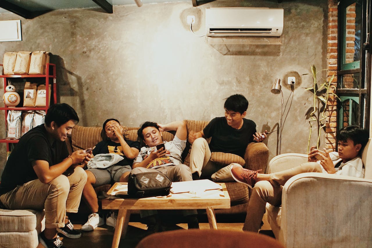 contact-header Five young men relaxing indoors, chatting and using phones in a Jakarta café.