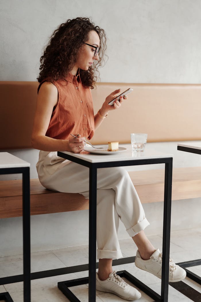about-01 A young woman enjoys a quiet moment at a coffee shop, checking her phone while seated.