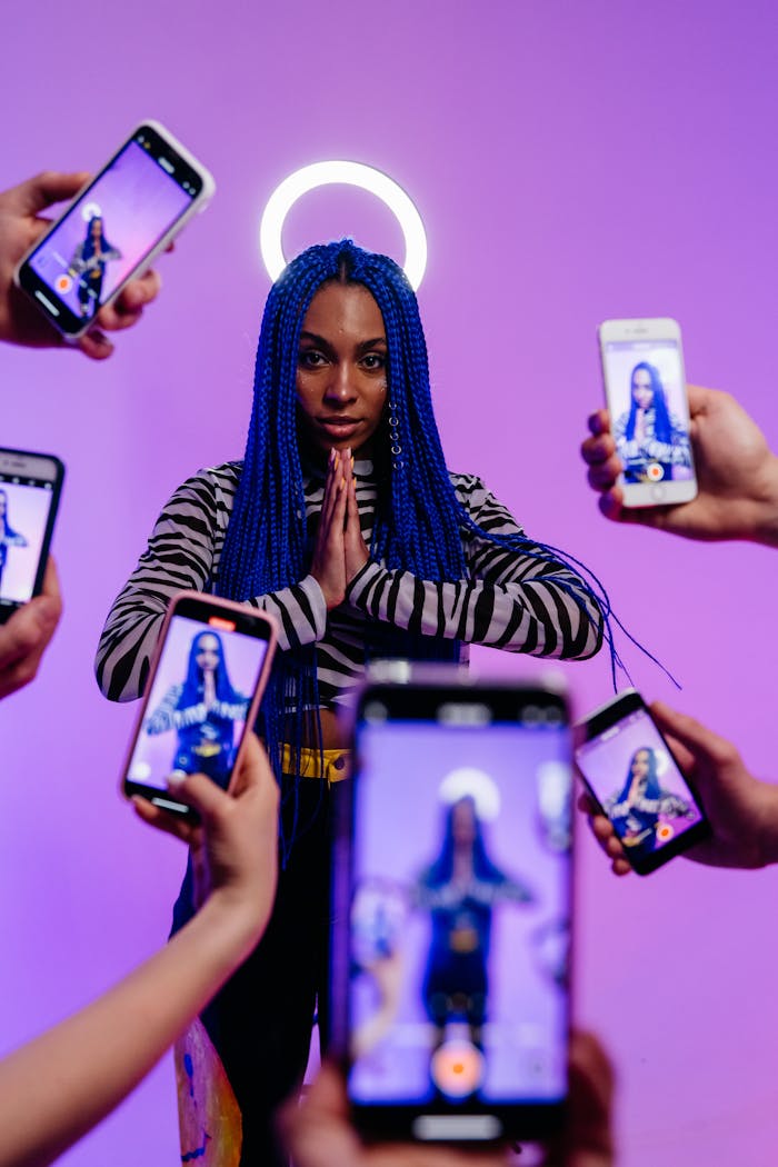 Creative studio shot of a stylish woman with blue hair surrounded by smartphones.
